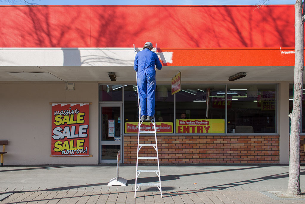 Image of Man on ladder painting outside of furniture store Tuesday, 11 July 2017