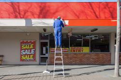 Thumbnail Image of Man on ladder painting outside of furniture store