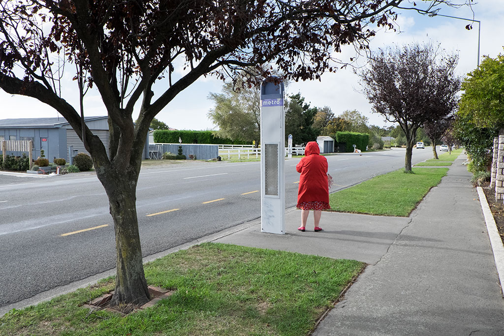 Image of Woman waits at bus stop on Dunbars Road. 15-04-2015 11.39 a.m.