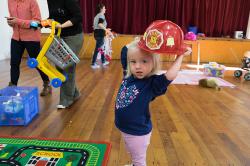 Thumbnail Image of Girl plays with fireman's hat at Little Steps community group