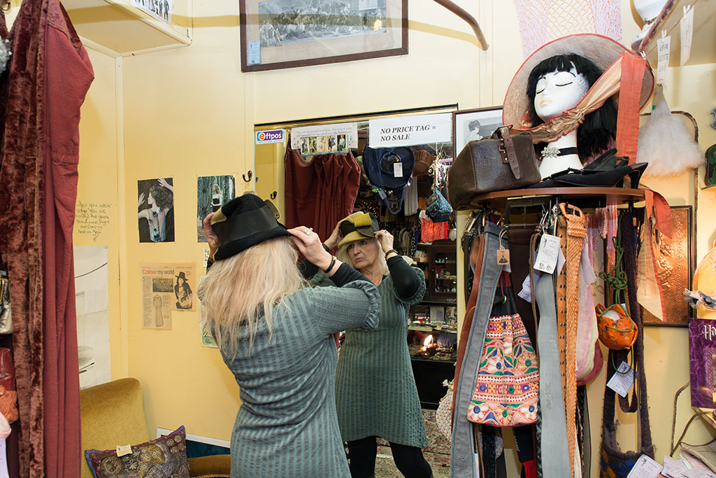 Image of Shelley tries on a hat at her shop 