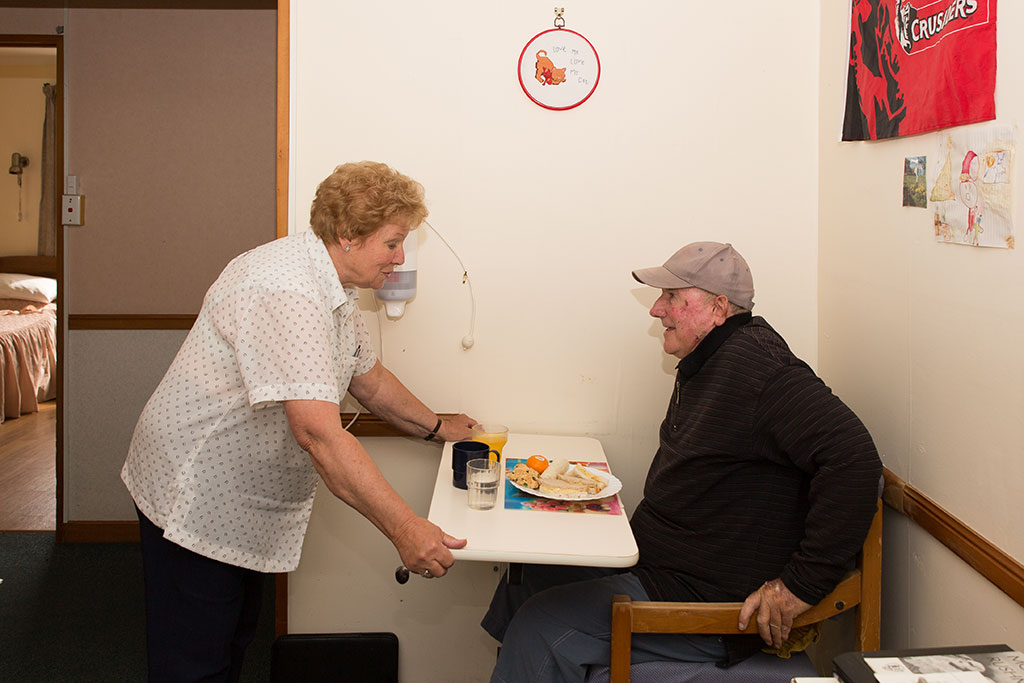 Image of A nurse serves lunch to Graeme at a rest home. 29-03-2016 12:20 p.m.