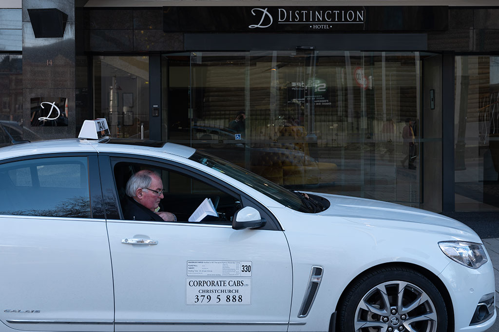 Image of Taxi driver reading, outside the Distinction Christchurch Hotel, 14 Cathedral Square. Friday, 8 June 2018