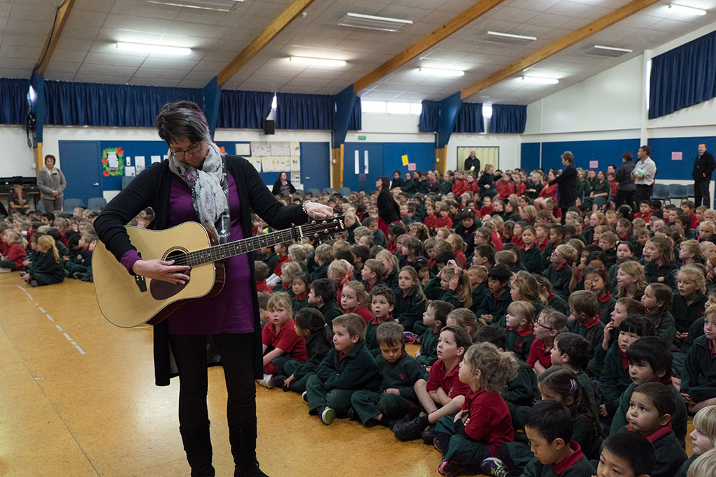 Image of Stacey, an Oaklands Primary School teacher, tunes her guitar before the school assembly. 25-05-15 2.07 p.m.