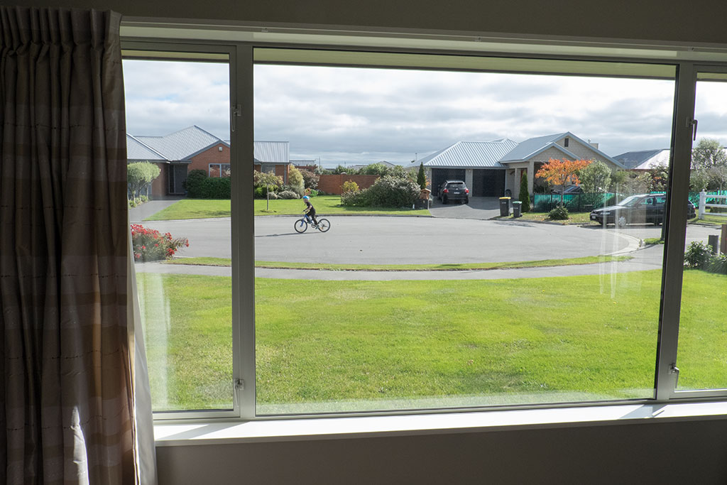 Image of Looking out of Karen's lounge window towards Marcella Gardens where a child rides his bike, Aidanfield subdivision. 23-04-2015 12.54 p.m.